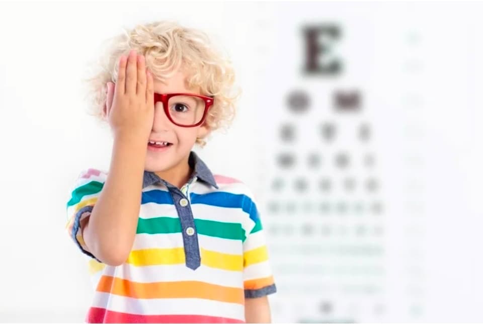 Child with glasses and an eyetest in the background